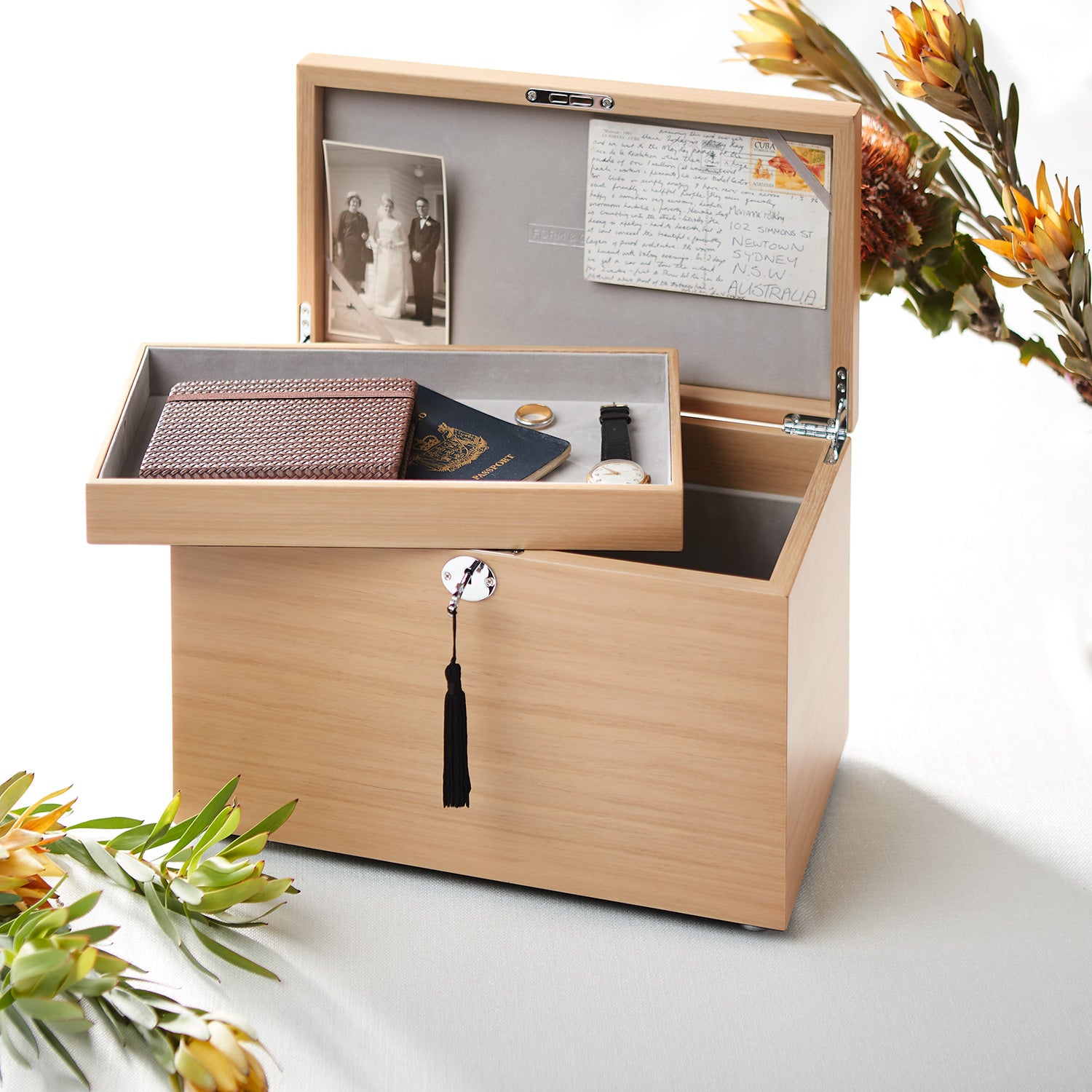Wooden memory box with photos, letters, and a watch on a white background