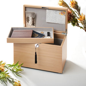 Wooden memory box with photos, letters, and a watch on a white background