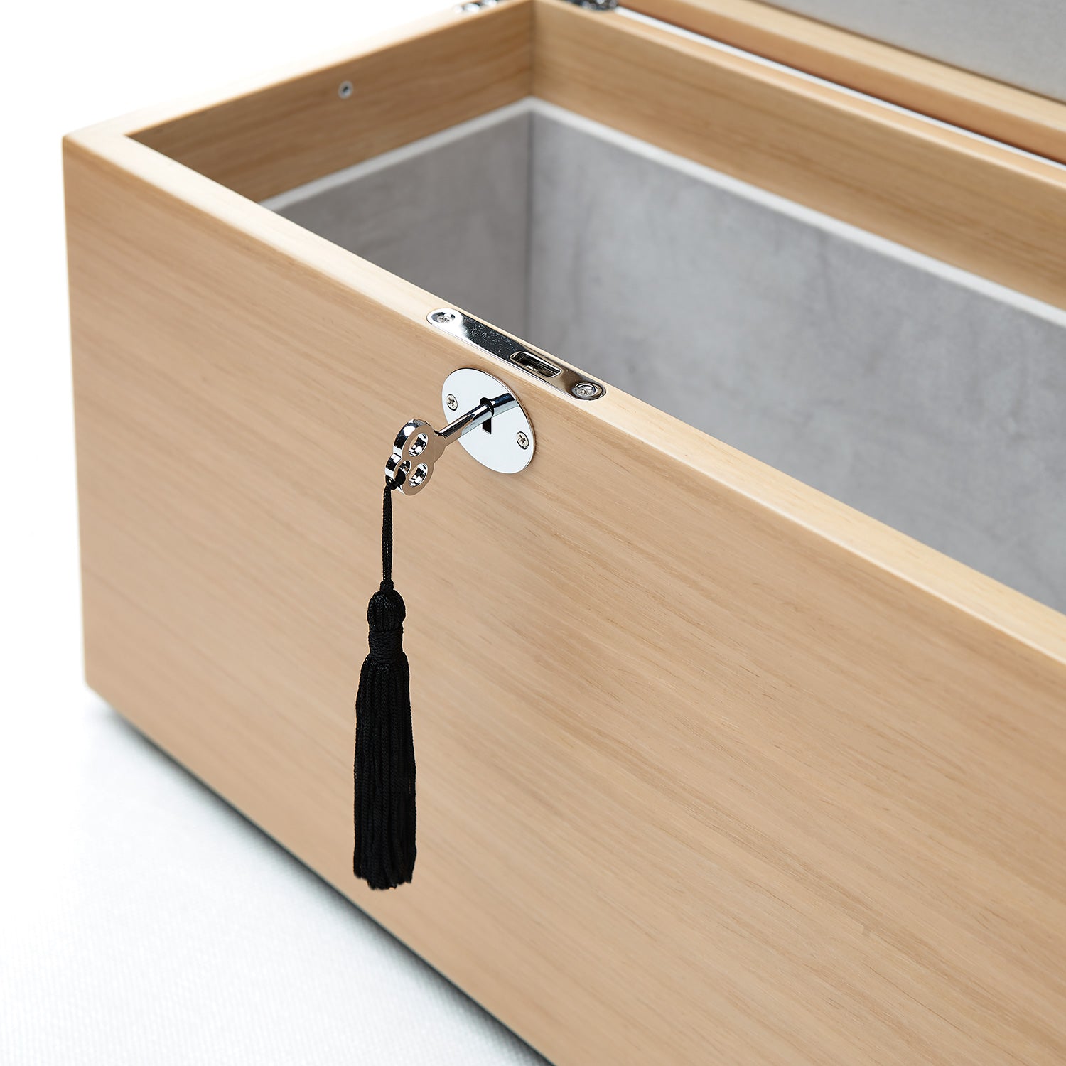 Wooden box with a black tassel hanging from a hook on a white background