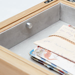 Wooden box with gray interior holding stationery items.