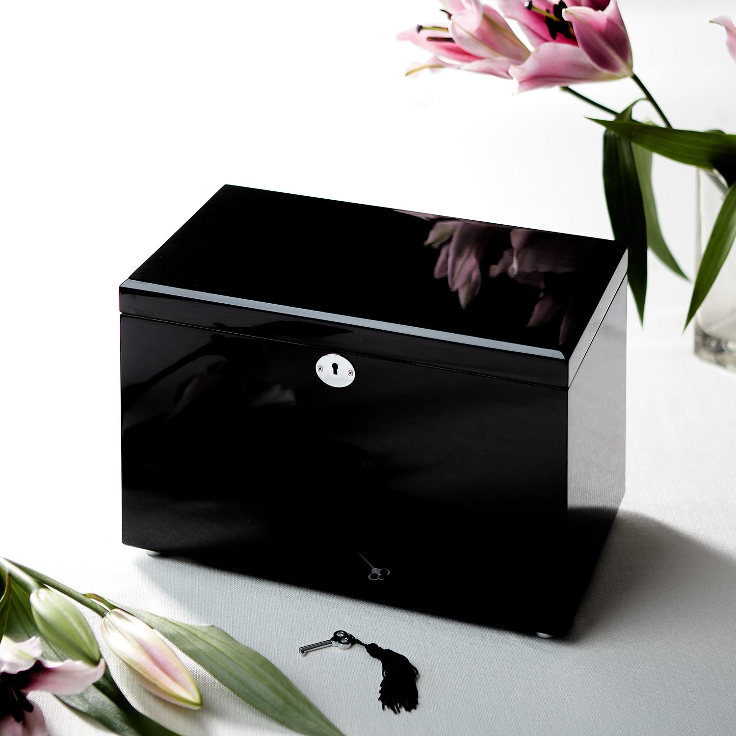 Black jewelry box with a lock on a white surface with flowers around