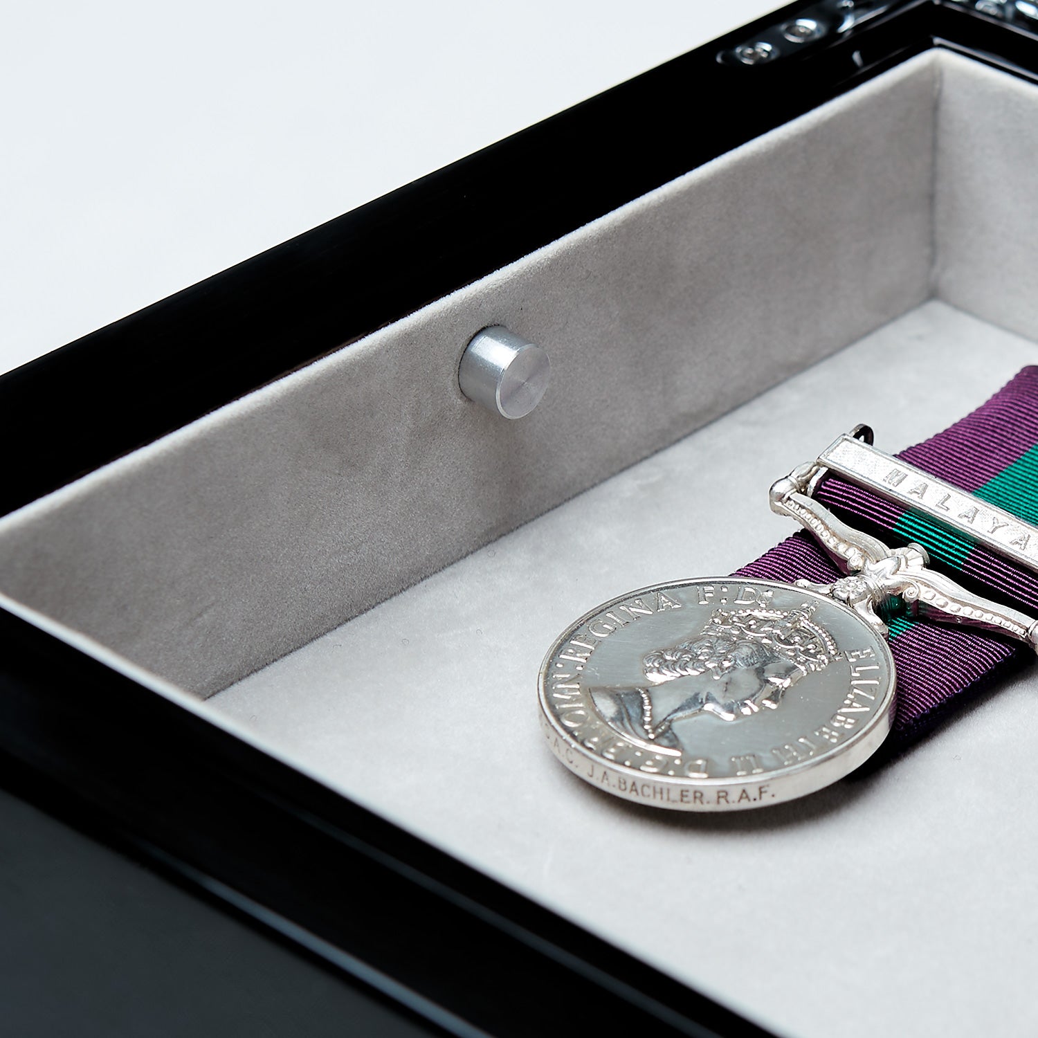 Silver medal with a purple ribbon in a display case