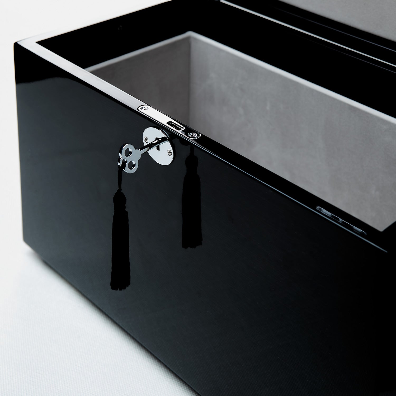 Black rectangular box with a silver clasp and tassel on a light gray background