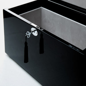 Black rectangular box with a silver clasp and tassel on a light gray background