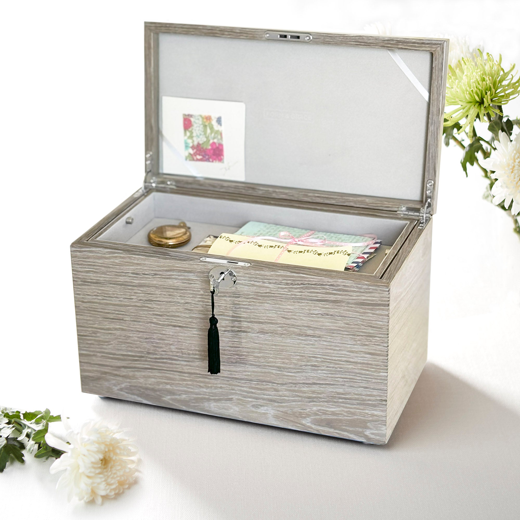 Decorative wooden box with an open lid on a white surface with flowers.